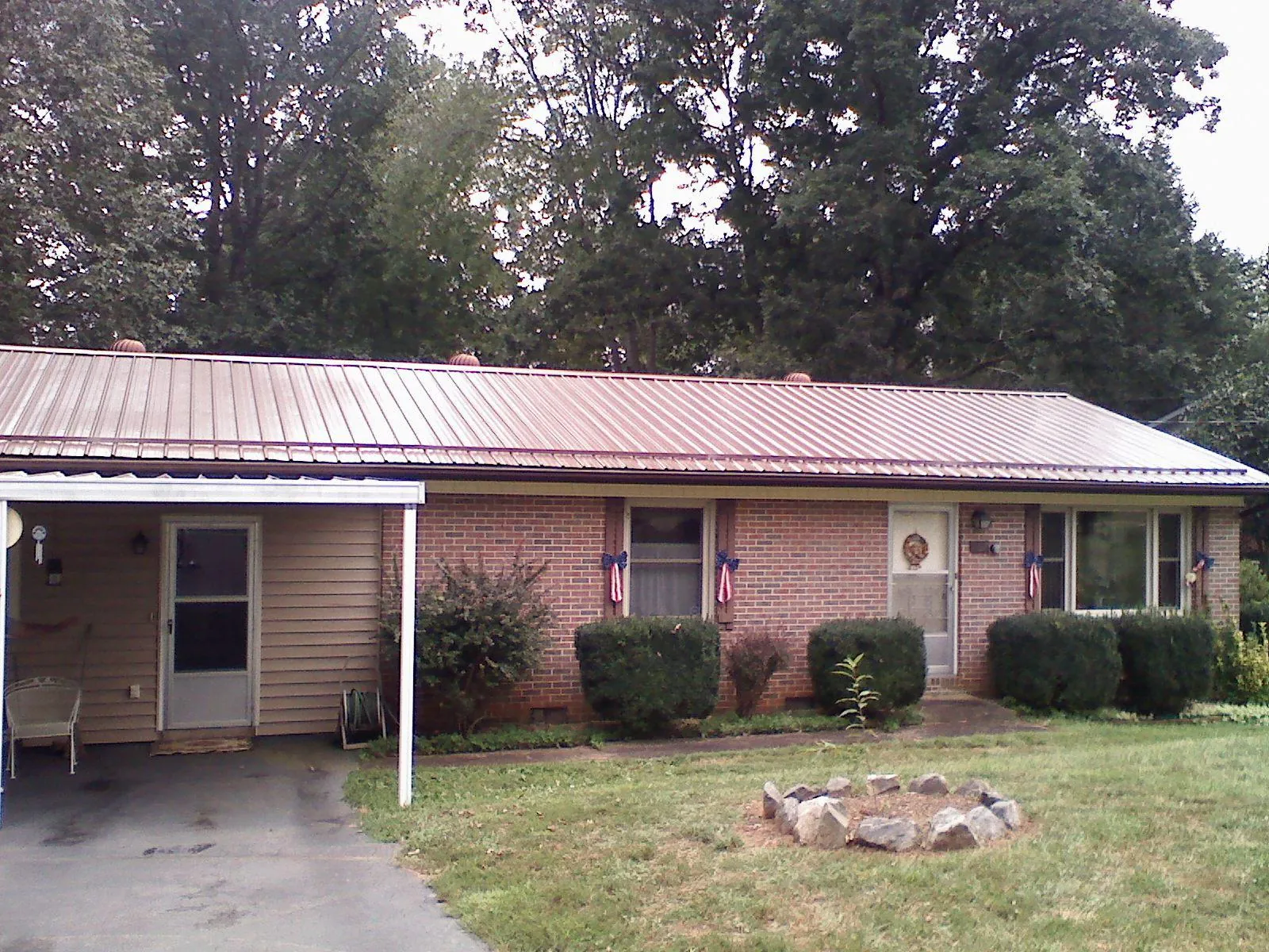 Bronze metal roof and carport on a brick ranch home — Roof Repair work by our crew in Lyndonville