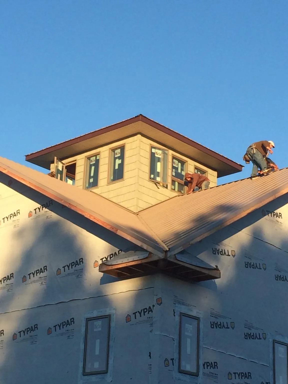 Roofers working around a rooftop cupola on a new metal roof at sunset — Roof Waterproofing in Lyndonville by Roofing Brothers